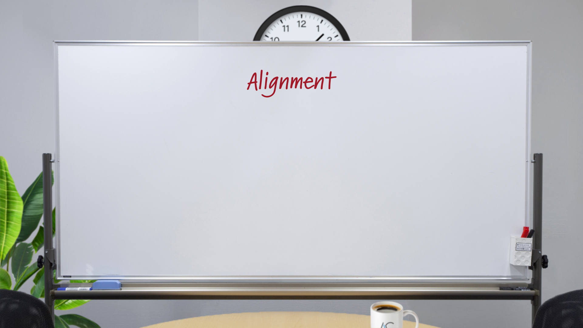 Whiteboard, in an office setting with a clock, conference table, steaming coffee mug, and plants, with the word "Alignment" written on it in red marker.